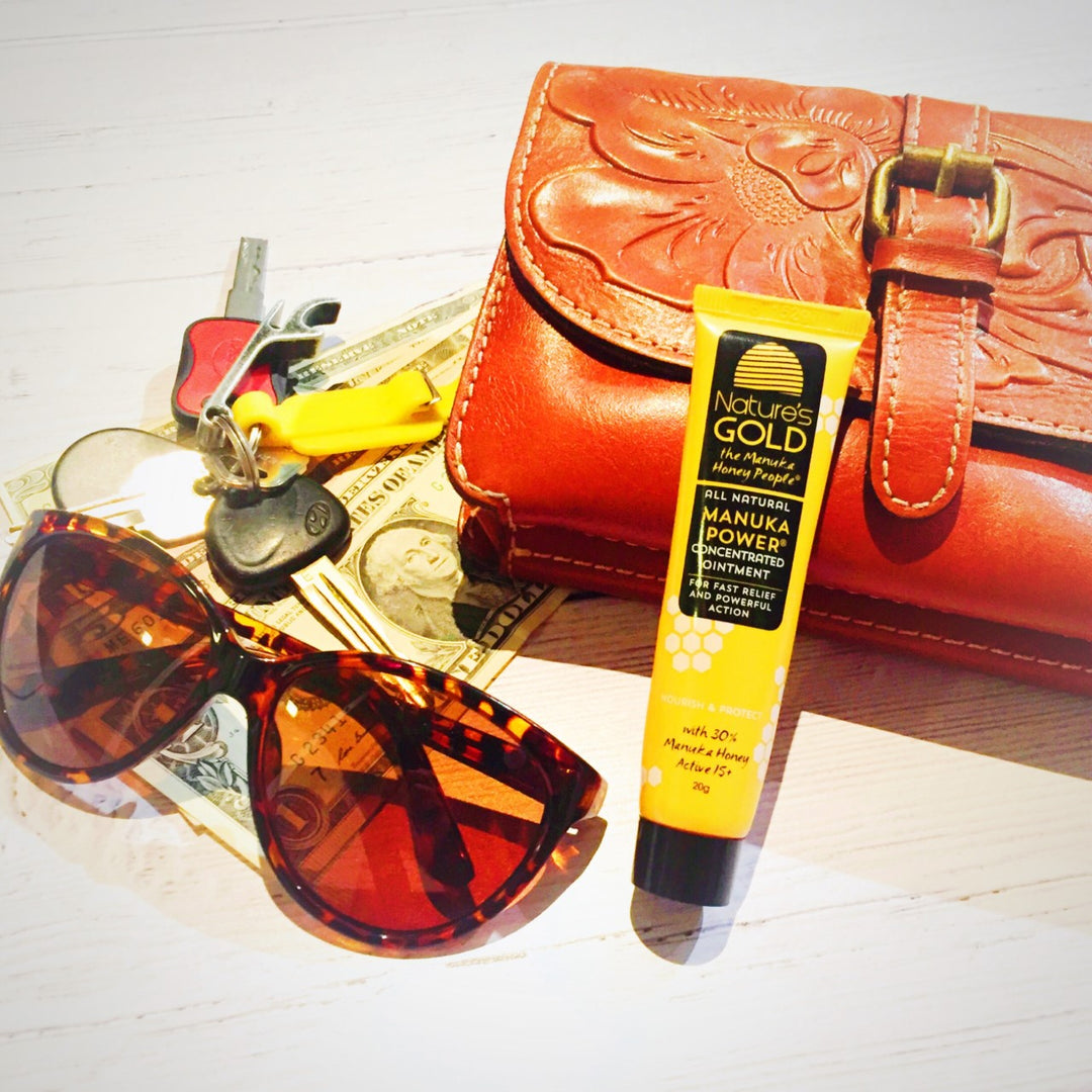Manuka power concentrated ointment tube with a leather purse and money, keys, and sun glasses