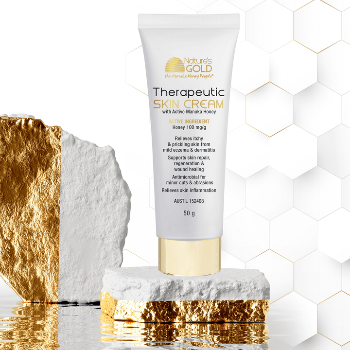 Therapeutic skin cream with active manuka honey on white and gold stone display
