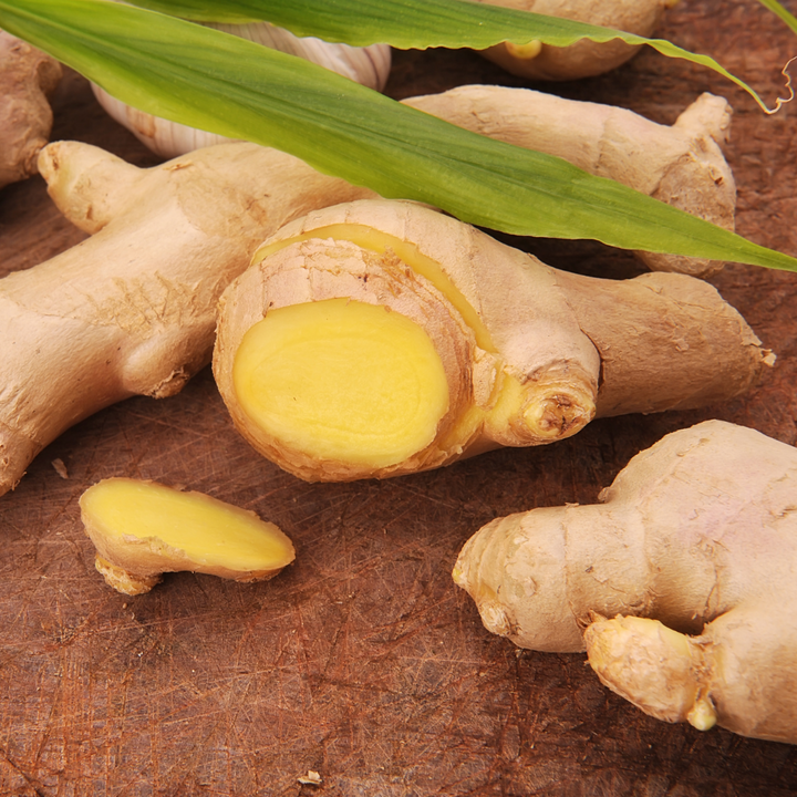 Cut ginger on a wooden table with a green leaf on top