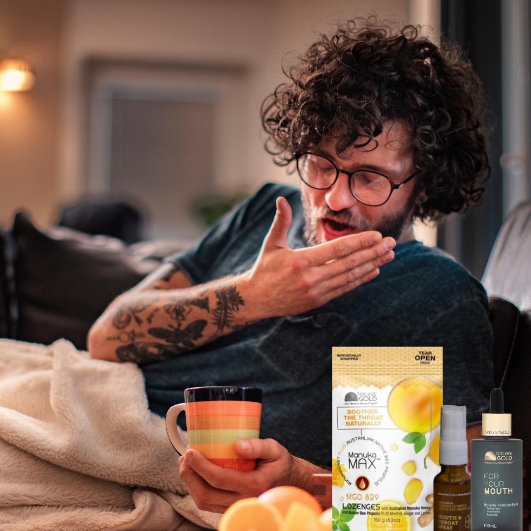 A man wearing glasses coughing in bed with Manuka Max and For Your Mouth Nature's Gold products