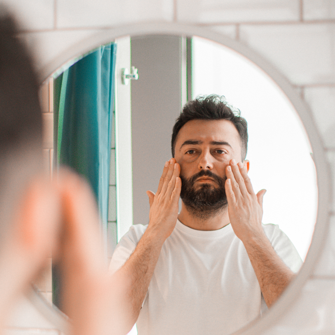 A man applying facial cream in front of a mirror 